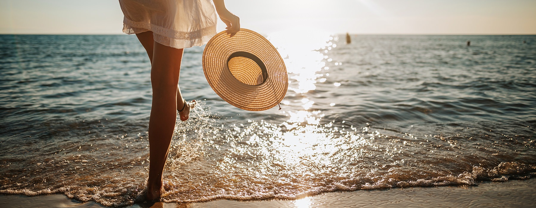 Woman walking on the beach in the sunset